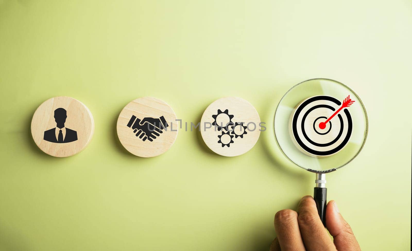 Focus through a magnifying glass onto the target goal icon, representing his dedication to corporate development, global business leadership, and effective strategies for success.