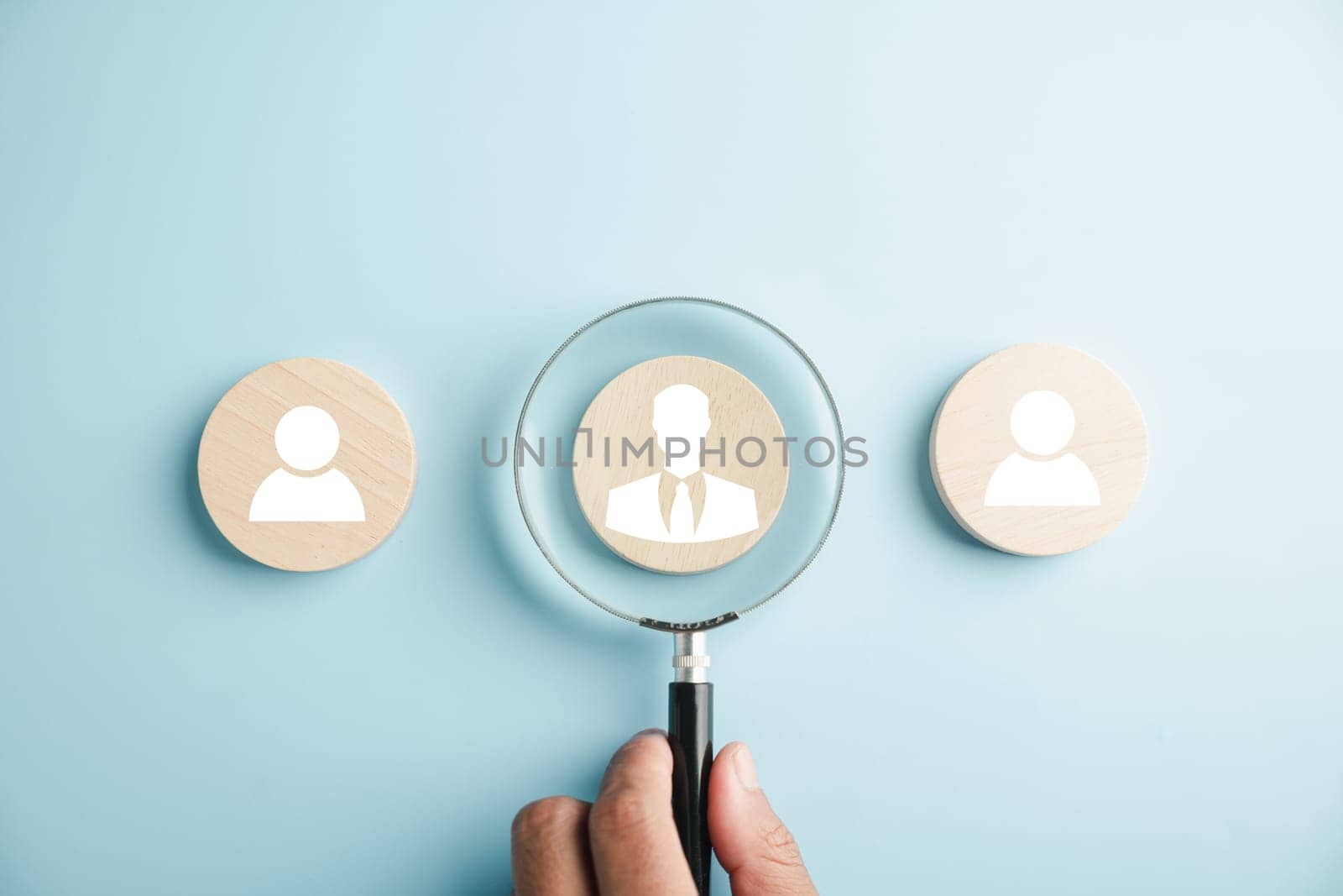 HRM insight Magnifier glass zooms in on manager icon in staff icons, representing the valuable role of human resource management in recruitment, leadership, and customer targeting. employees selection