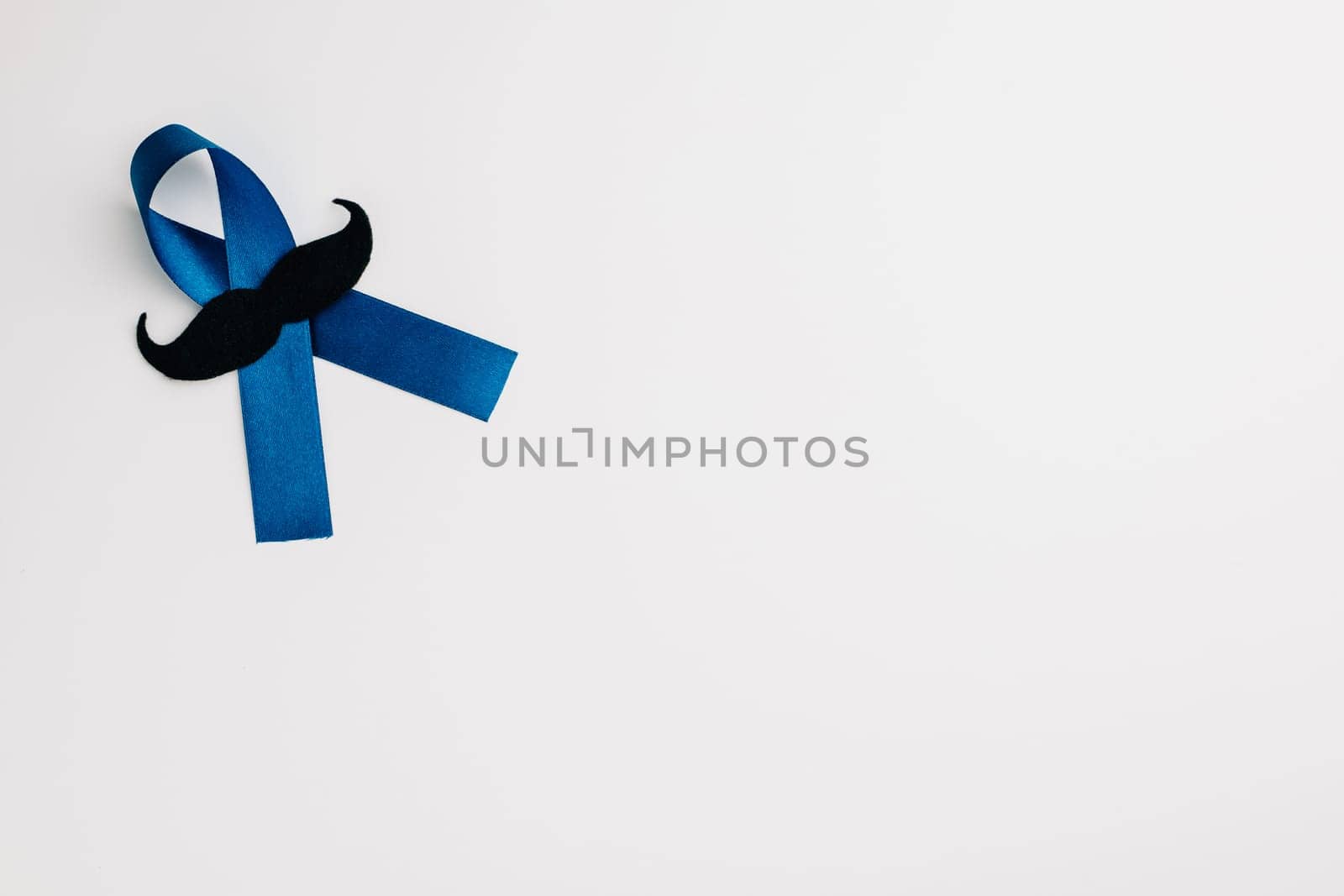 Top view of a blue ribbon with a mustache, a symbol for supporting men's health, isolated on white. Perfect for healthcare, International Men's Day, and Father's Day.
