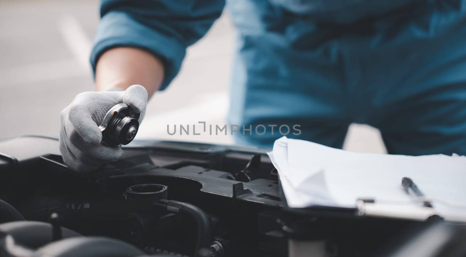 Male mechanic in garage, working on truck engine with dipstick. Horizontal photo of technician looking worried and distraught while checking liquid levels. Concept for car repair and insurance.