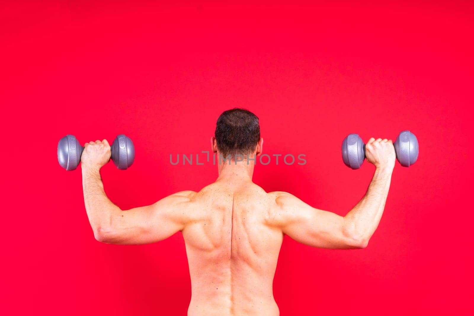 Handsome young fitness sporty strong guy bare-chested muscular sportsman on a studio background