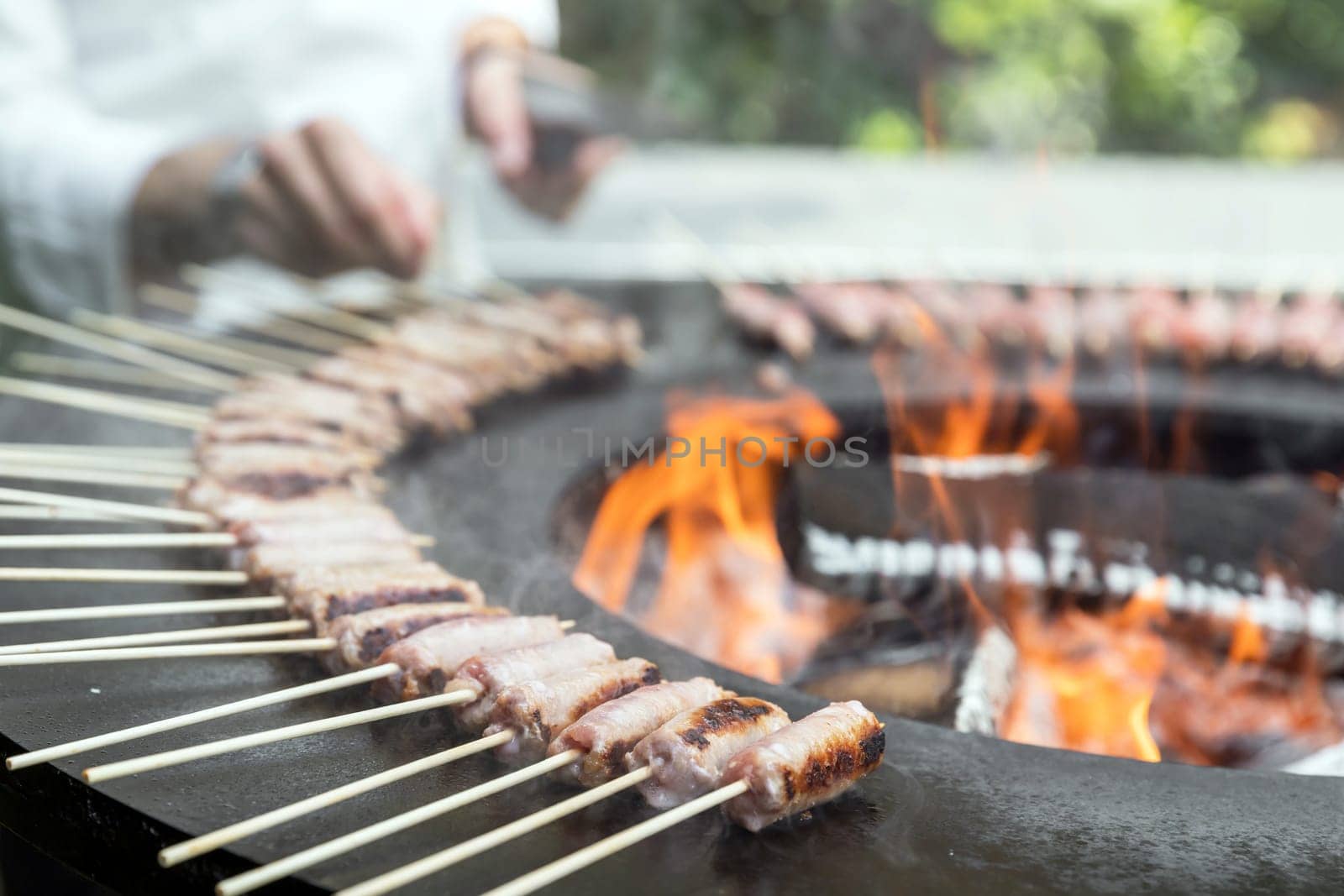 Sausage cooking on a wood brazier. This new concept enhances the advantages of cooking barbecue on a wood brazier.