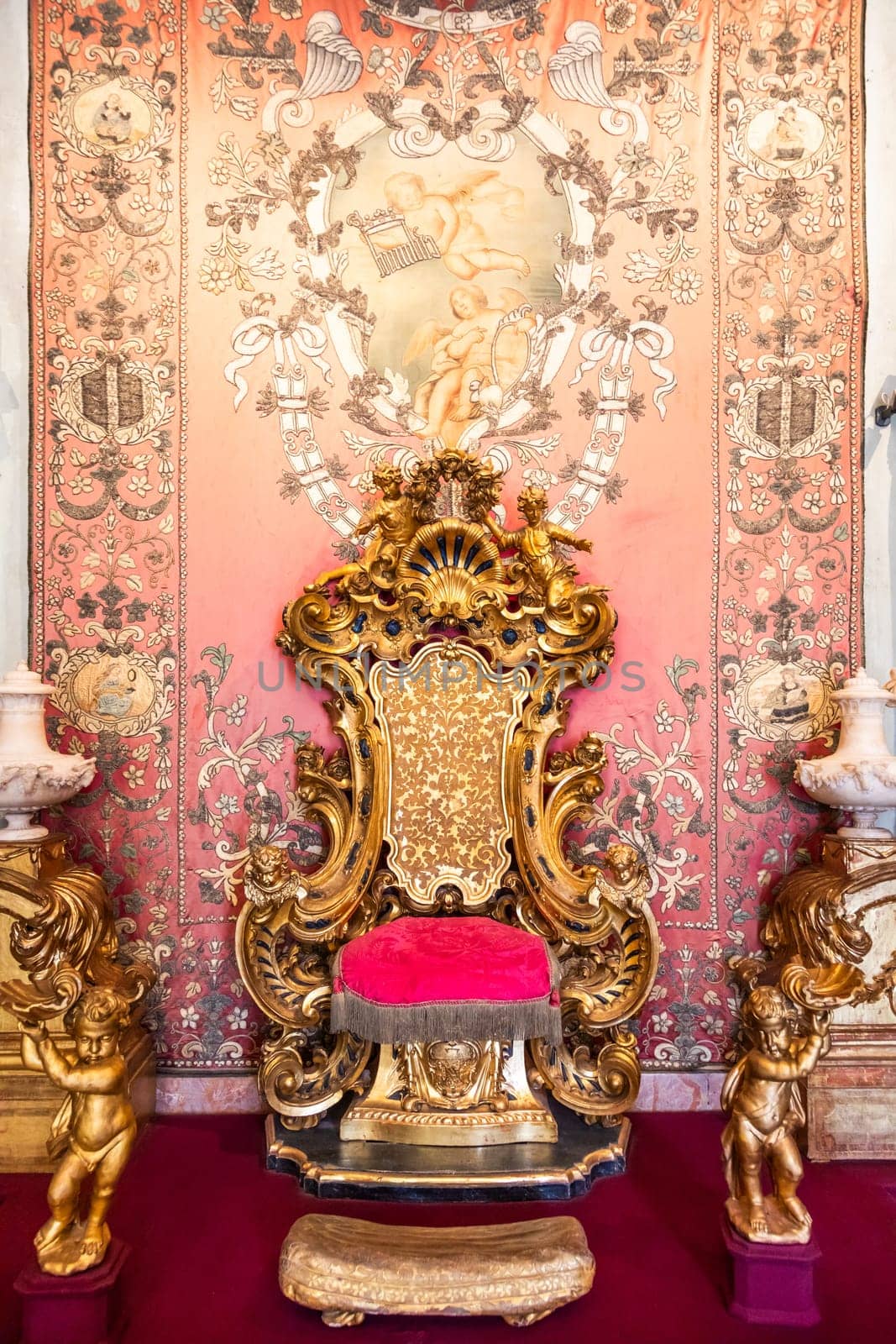 Isola Bella, Italy - 1 August 2023: antique throne in gold and red velvet. Old royal chair, luxury vintage.
