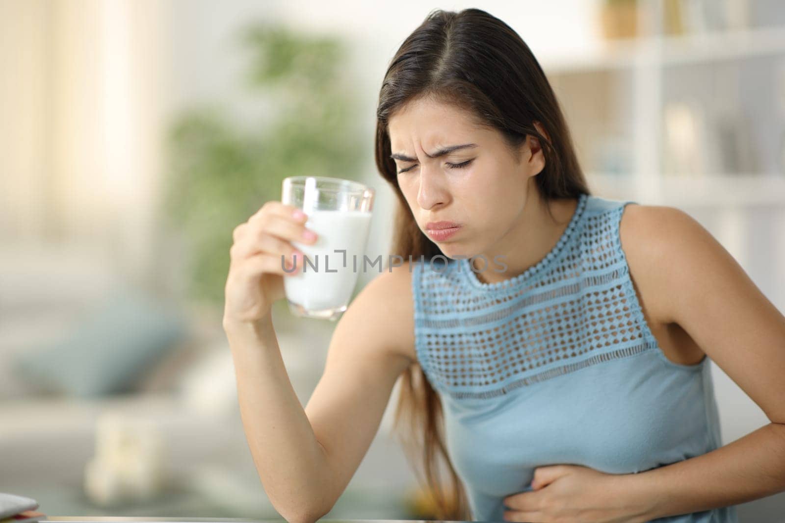 Woman suffering belly ache drinking milk at home