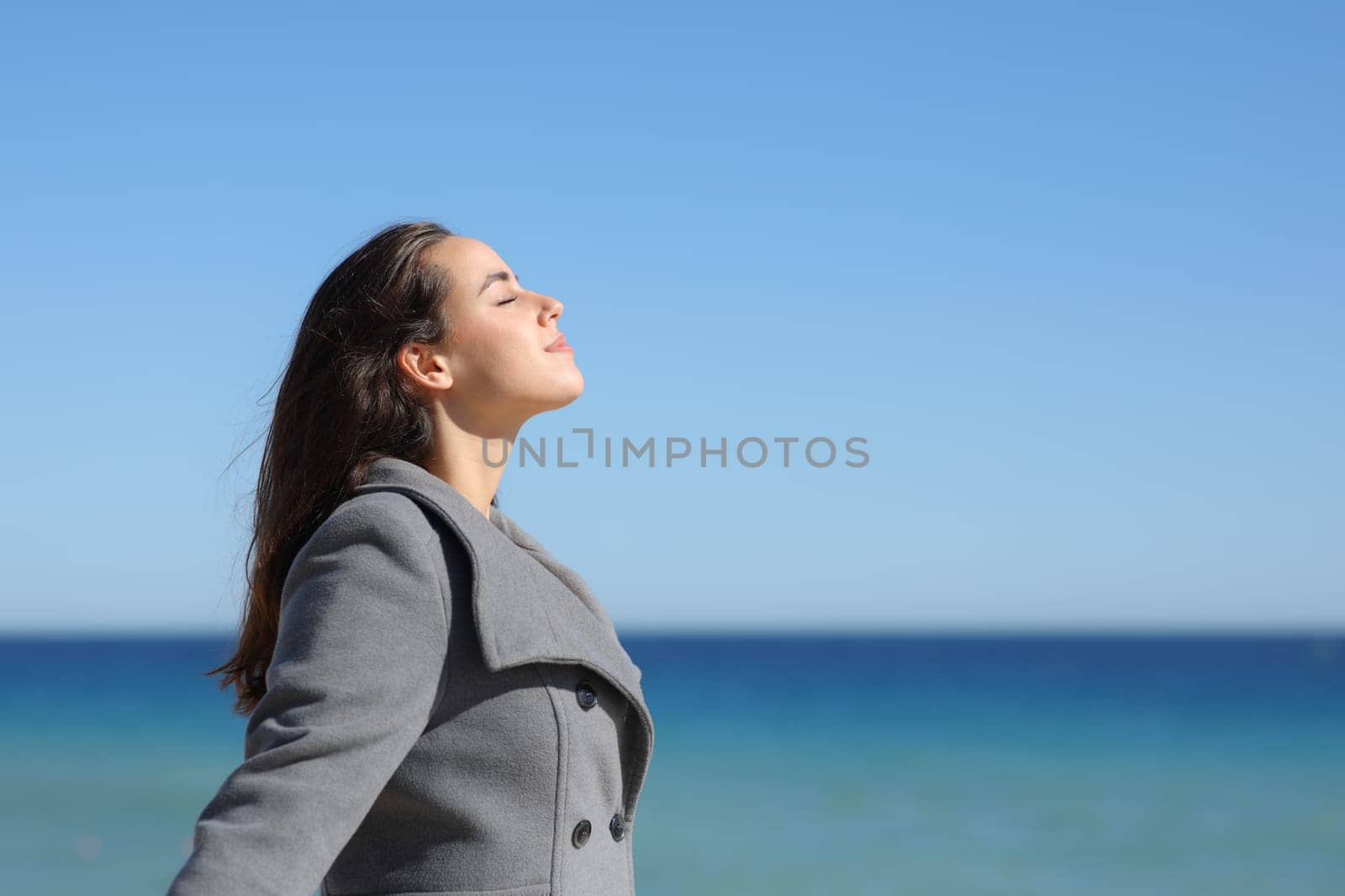 Side view portrait of a relaxed woman in winter breathing fresh air on the beach
