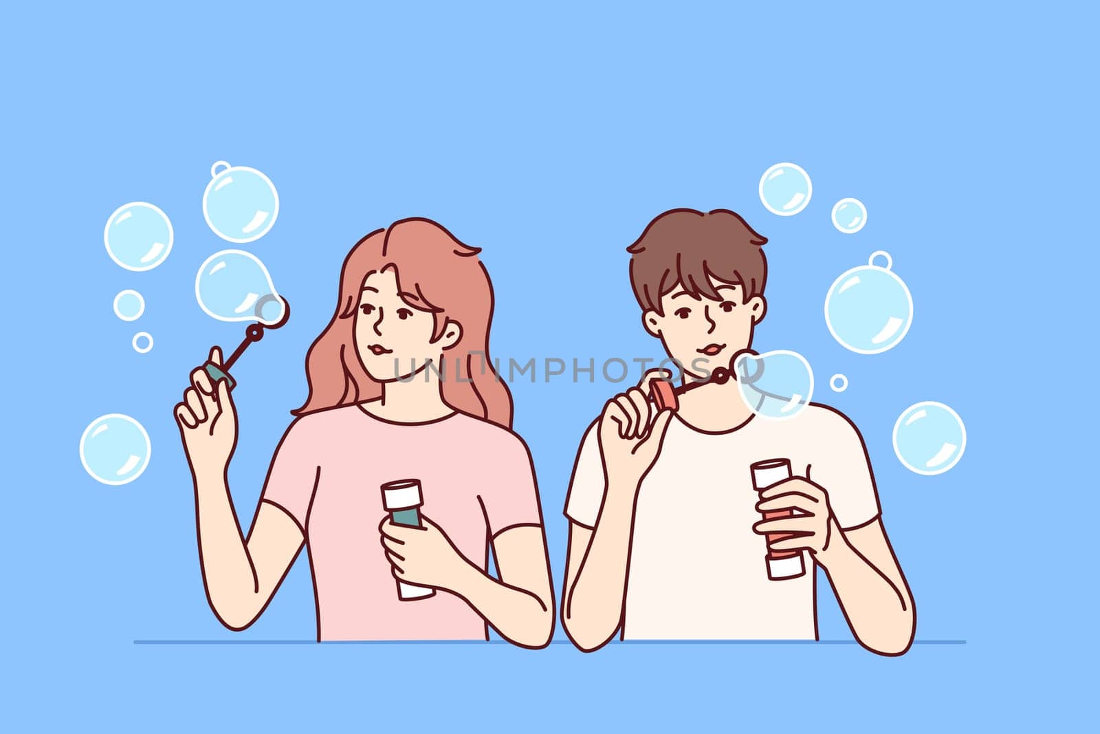 Man and woman inflate soap bubbles and have fun in free time, enjoying pastime together. Couple of casual teenagers with soap bubbles in hands playing and refusing to do useful things