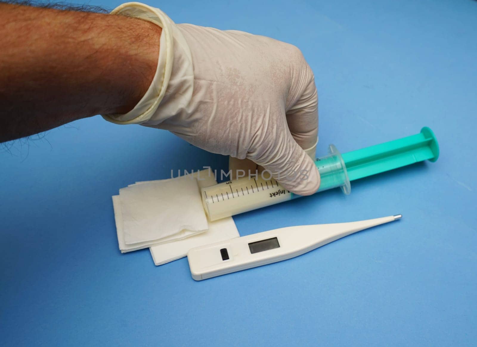Hand with digital clinical thermometer and syringe on blue background