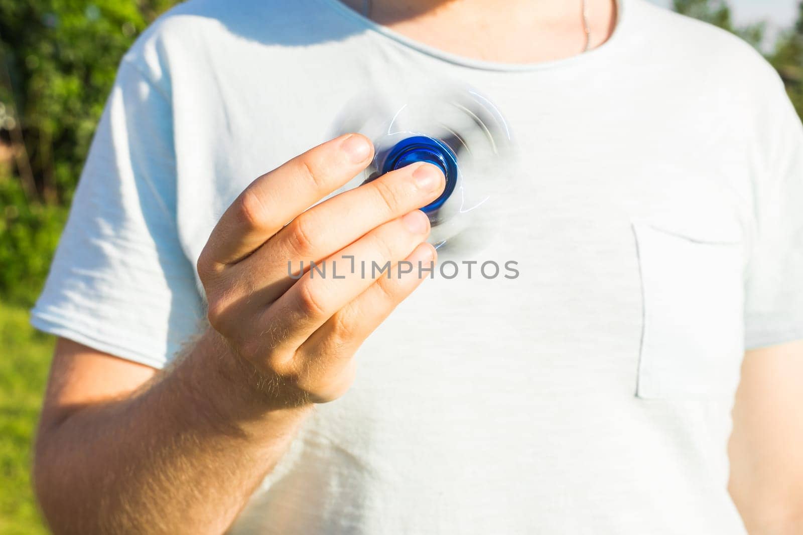 Man playing with a blue spinner fidget toy, close up.
