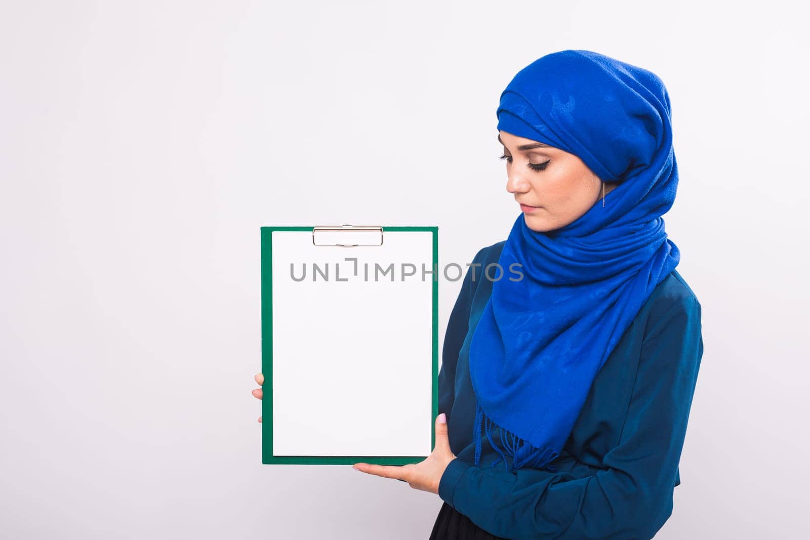 Your text here. Pretty young excited Arab woman holding empty blank board. Colorful studio portrait with white background