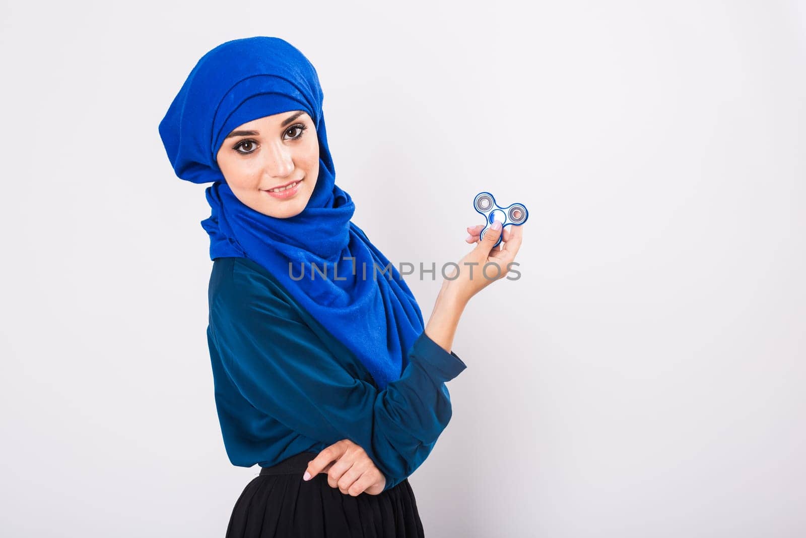 Young beautiful muslim girl holding and playing with fidget spinner. studio shot on white background