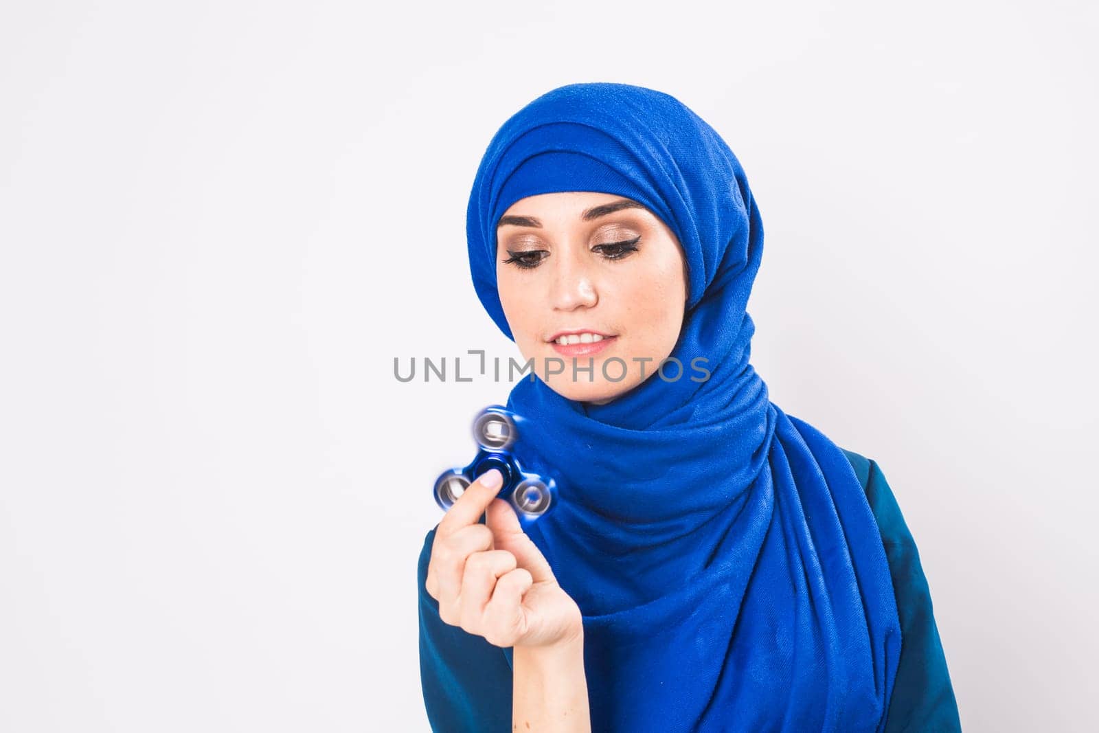 Young beautiful muslim girl holding and playing with fidget spinner. studio shot on white background