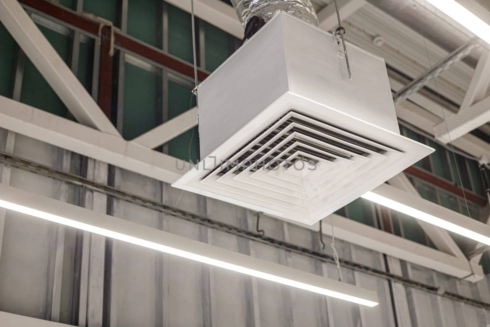 Square grille distributor with supply ventilation duct in a commercial building. Industrial office ventilation system