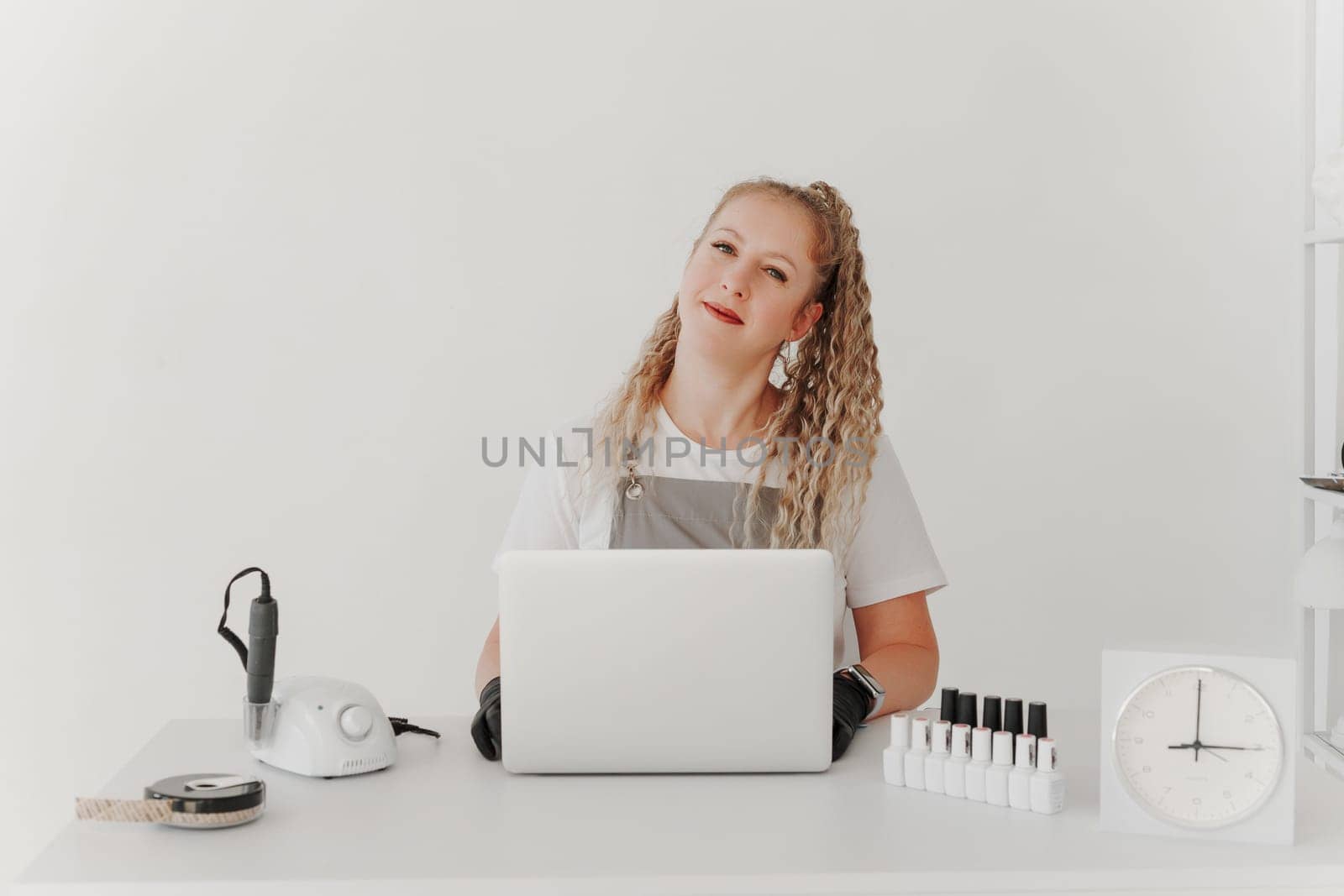 Woman Professional Manicurist at her Desk Works with a Laptop. Sign up for manicure services, freelancer work schedule