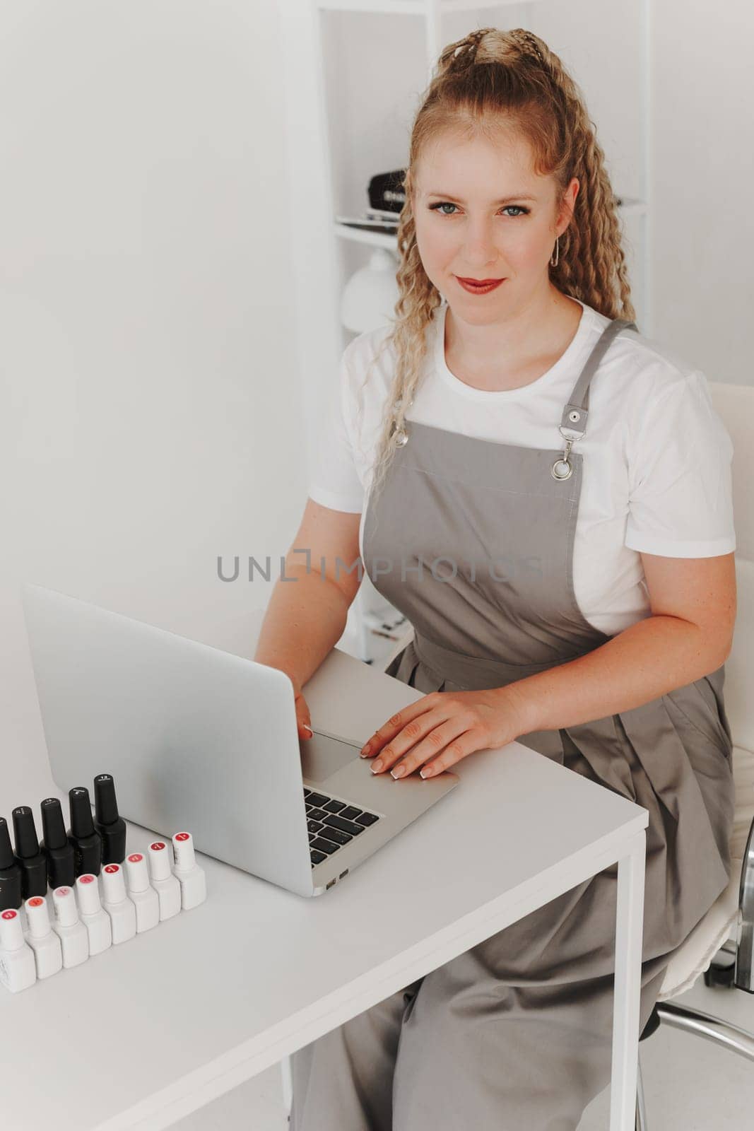 Woman Professional Manicurist at her Desk Works with a Laptop. Sign up for manicure Services, Freelancer Work Schedule