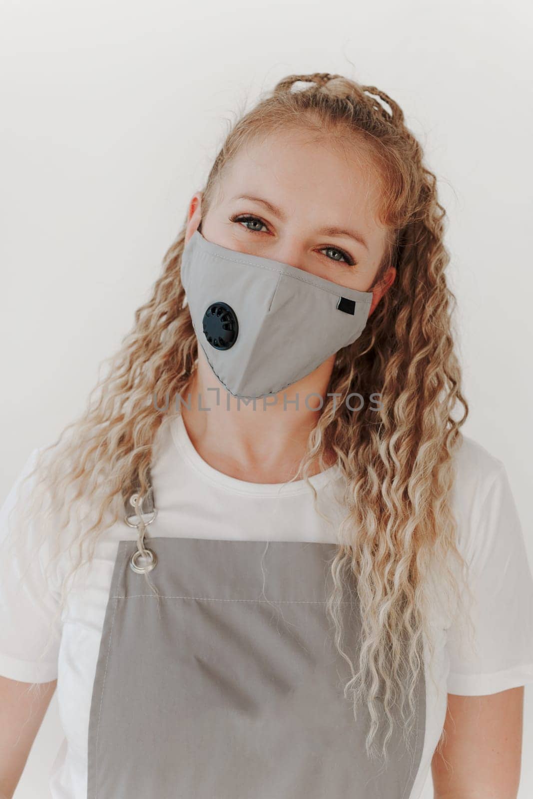 Close up portrait of Caucasian middle-aged woman in working uniform mask and apron looking at camera. White background