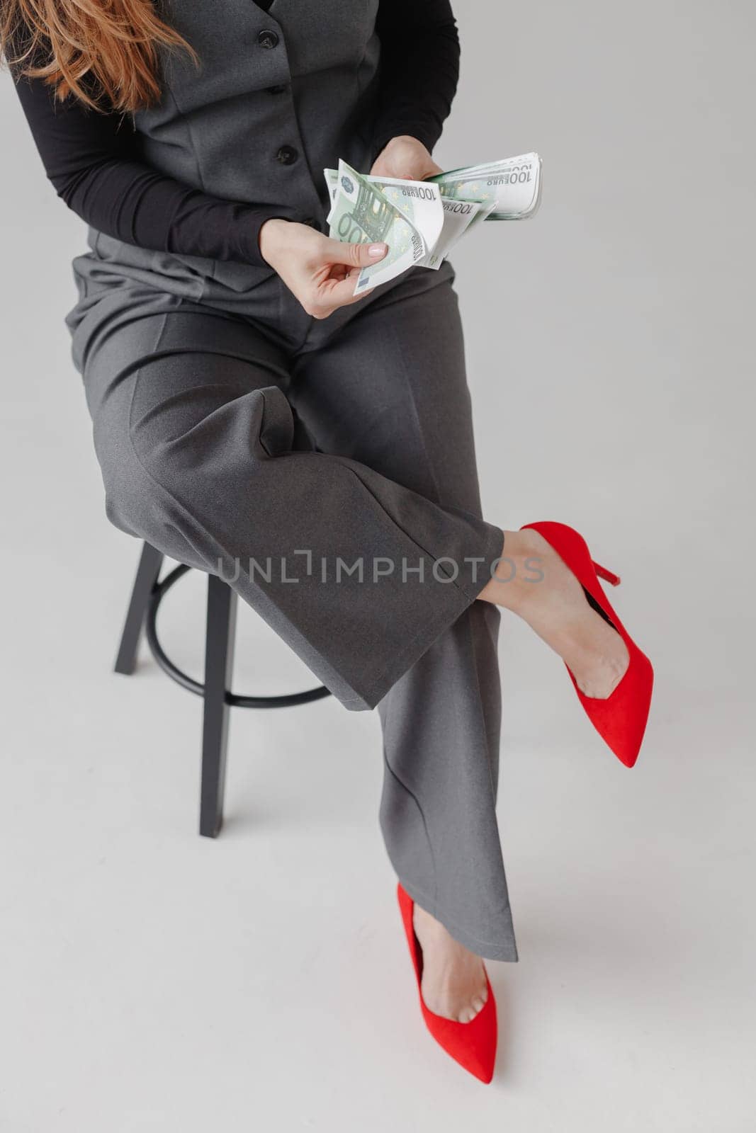 Woman in formal suit and red heels counting Euro money, on white background. Business lady concept.