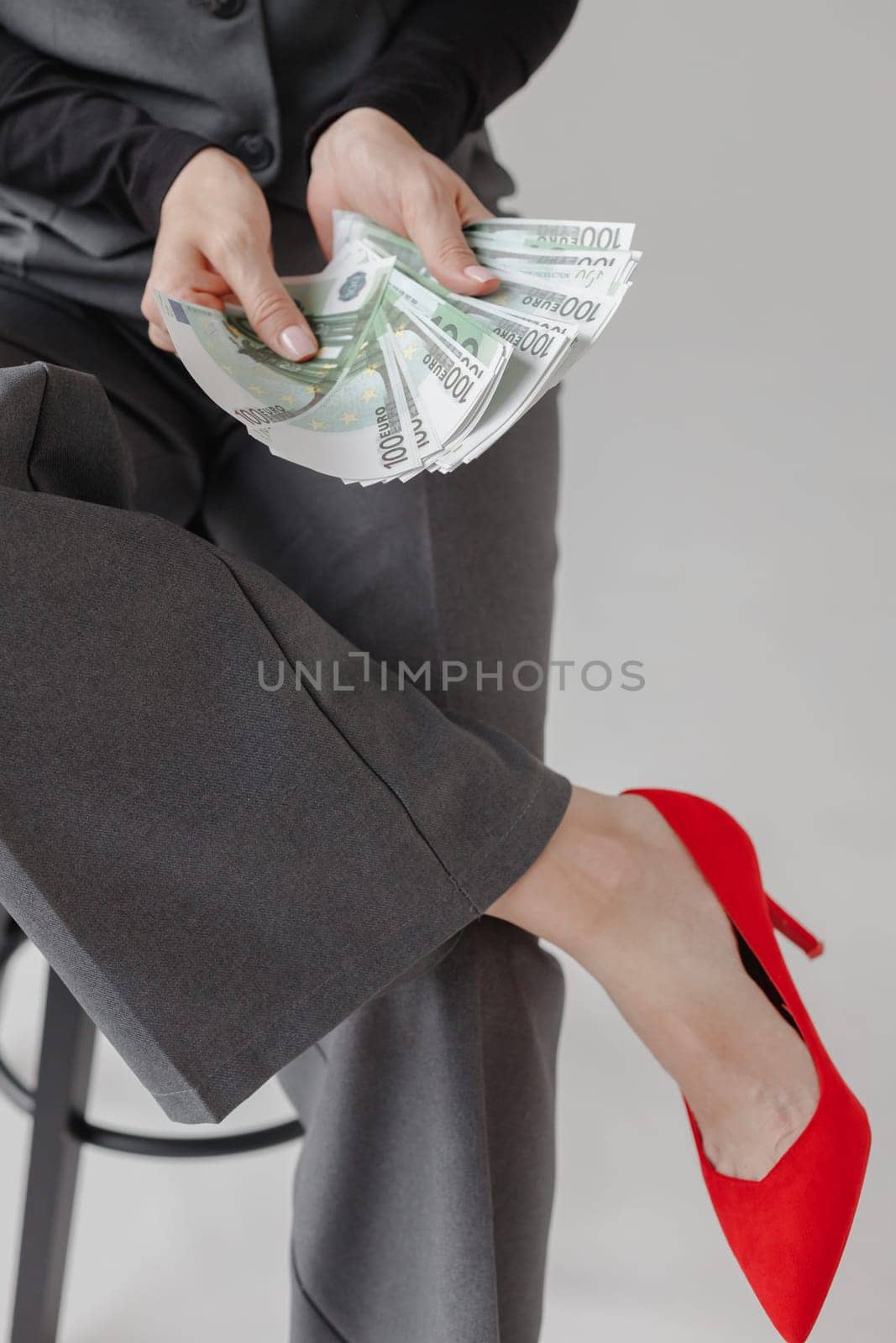 Woman in formal suit and red heels counting Euro money, on white background. Business lady concept.