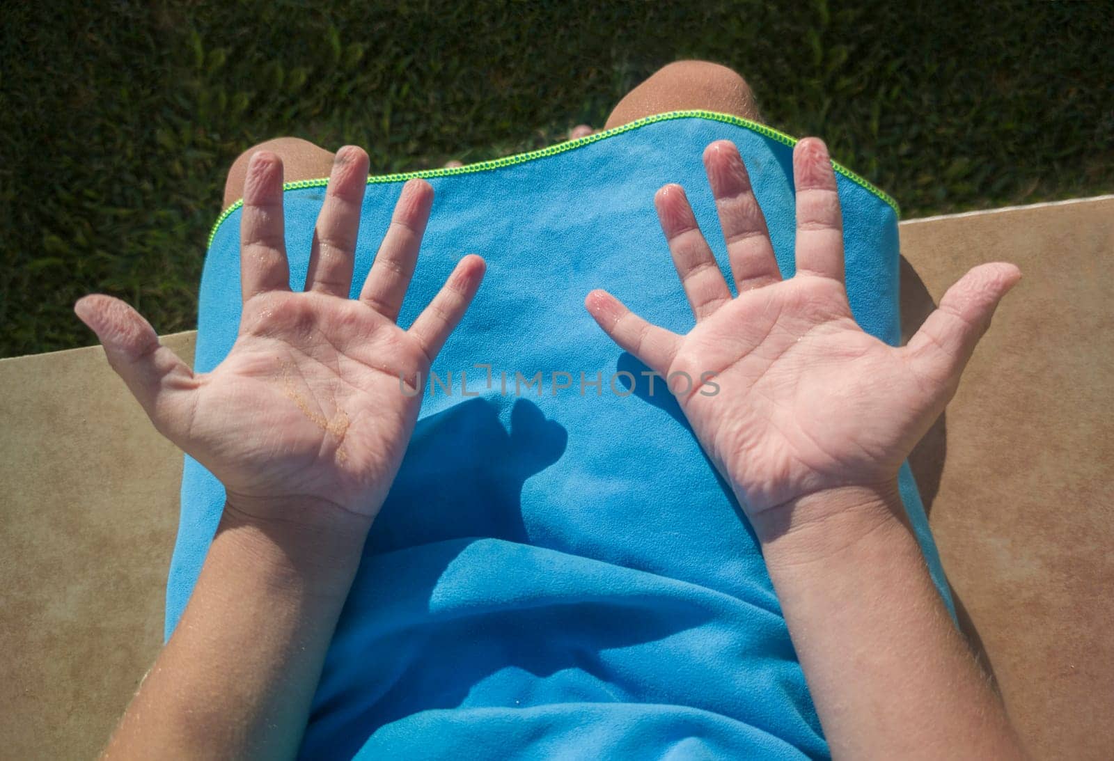 Child boy showing his wrinkled hands after swimming in the pool. Overhead view