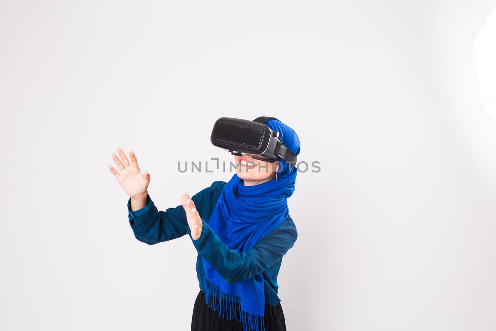 Asian muslim woman wearing hijab using VR headset glasses of virtual reality on white background