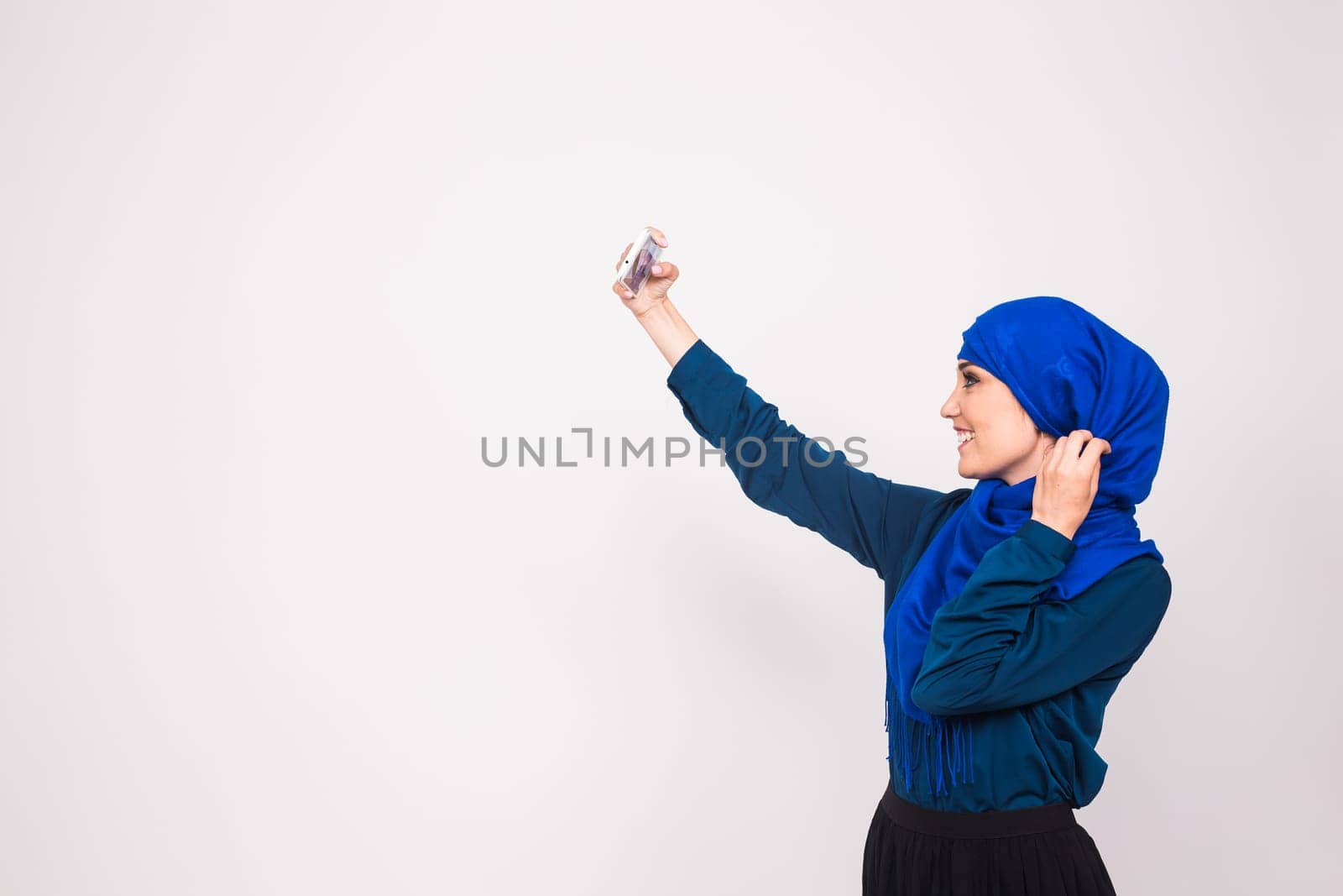 Portrait of beautiful muslim young woman wearing hijab take selfie using her mobile phone.