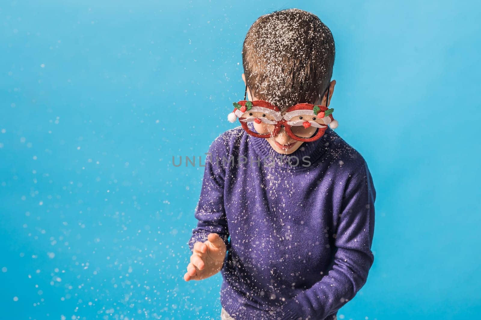 Child boy throws up on blue background. Christmas and New Year holidays concept. Generation alpha and gen alpha children. Copy space.