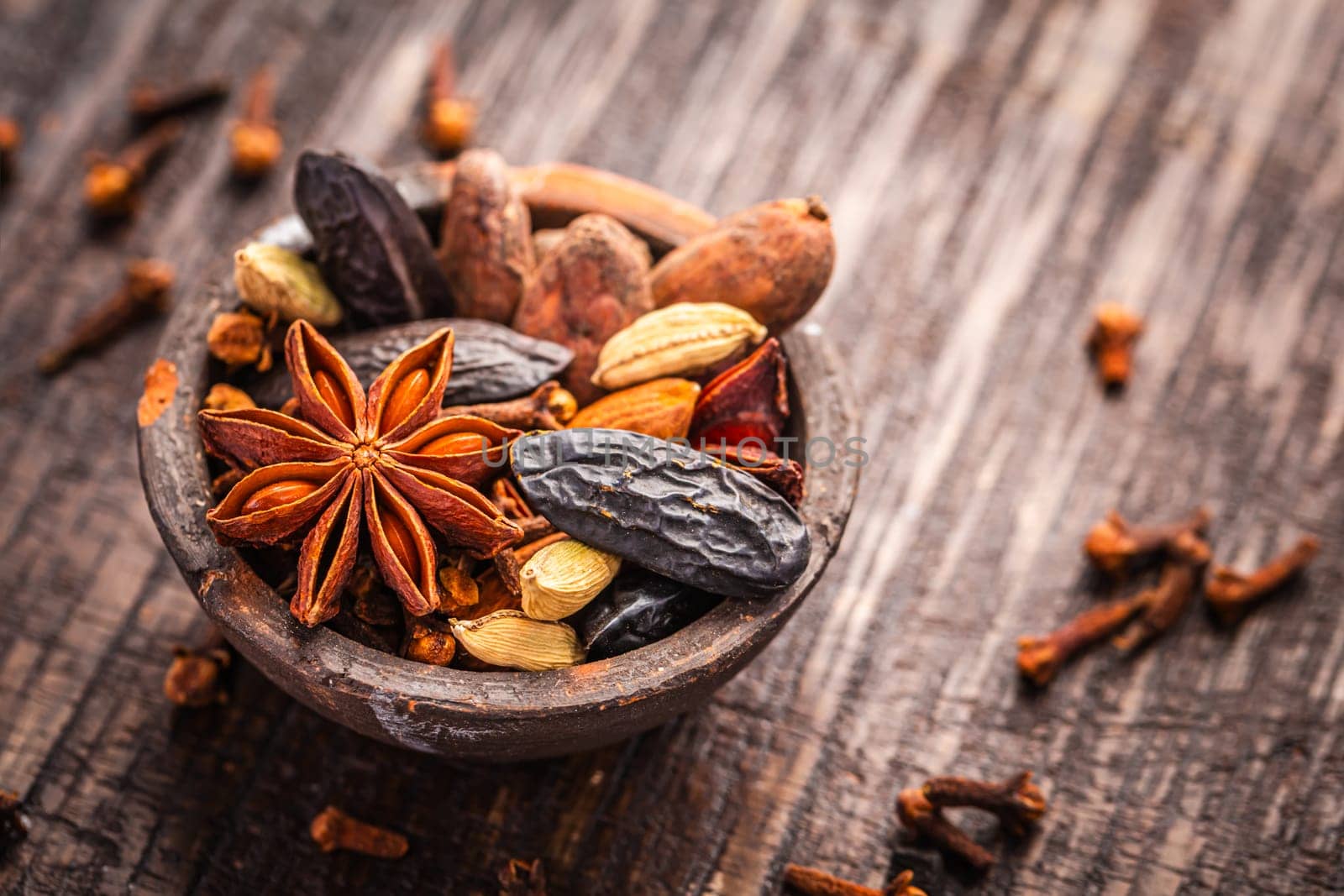 Christmas spices for baking cookies, Stollen or mulled wine in small bowl on wooden background.