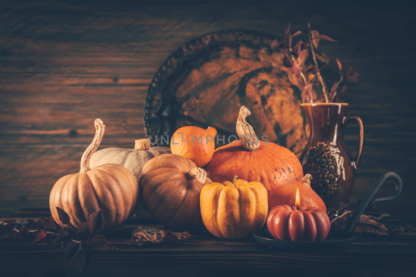 Autumn still life with pumpkins and candles on wooden background. Thanksgiving home decoration.