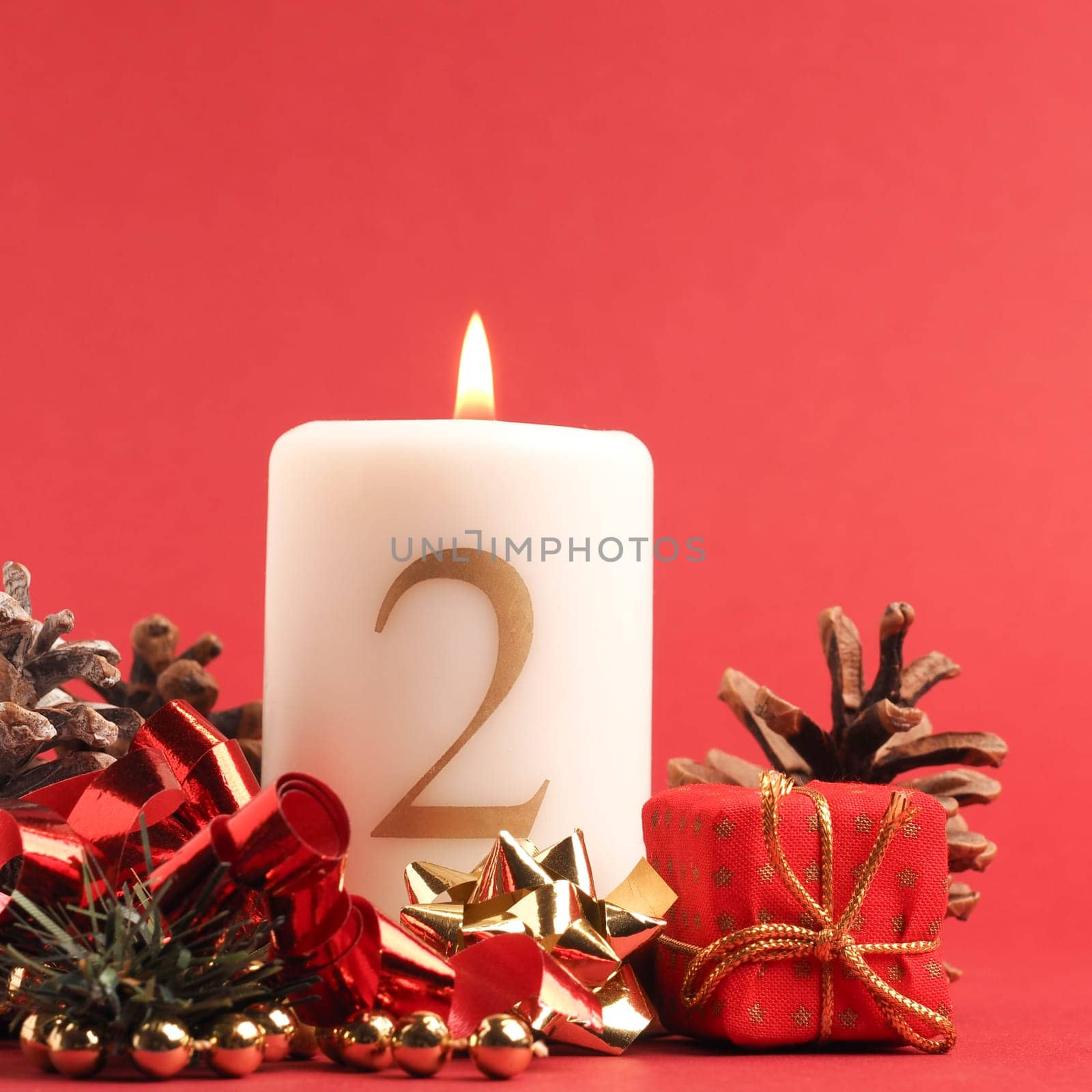 Second Advent candle burns, white candle with the number two on a red background, Christmas decoration, space for text