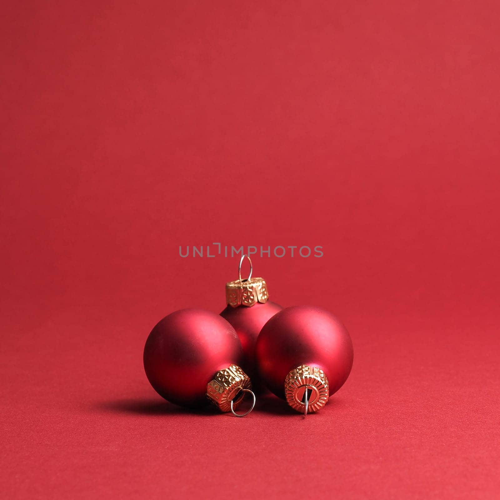 Three red vintage Christmas baubles on a red background with space for your text or image, seasonal holiday concept