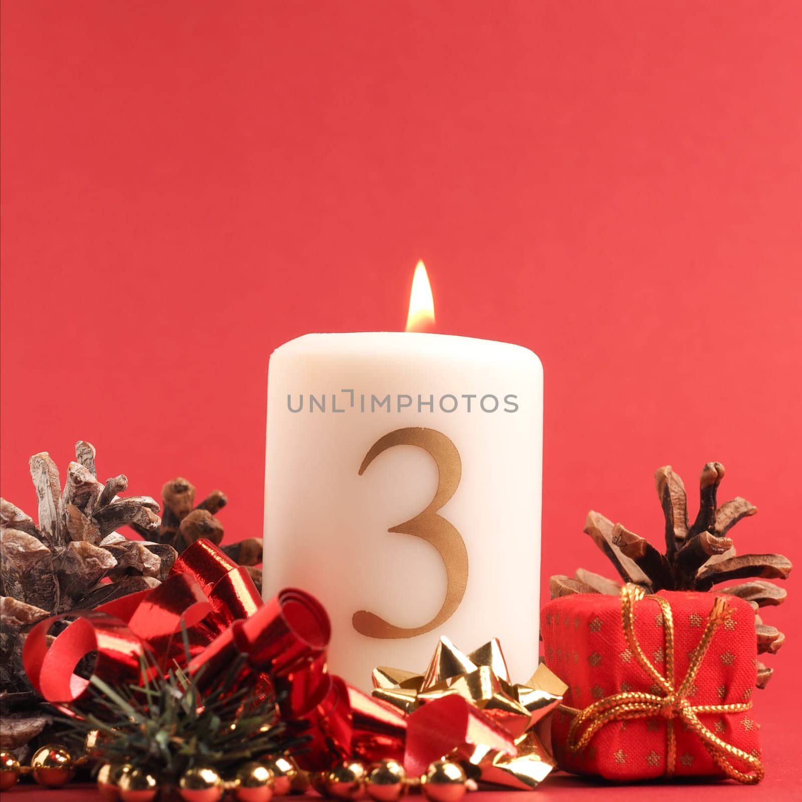 Third Advent candle burns, white candle with the number three on a red background, Christmas decoration, space for text