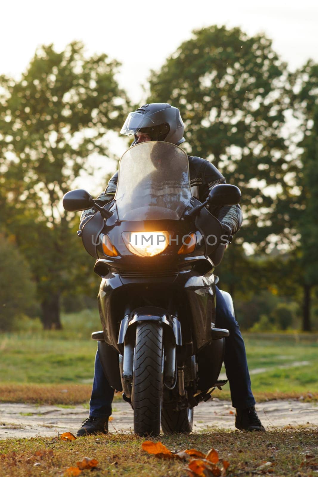 Vertical image. Unrecognizable person on motorcycle in nature in autumn during parking. Motorcycle tourism. Healthy . Sport and strength of character. Excellent physical shape. Motorcycle equipment.