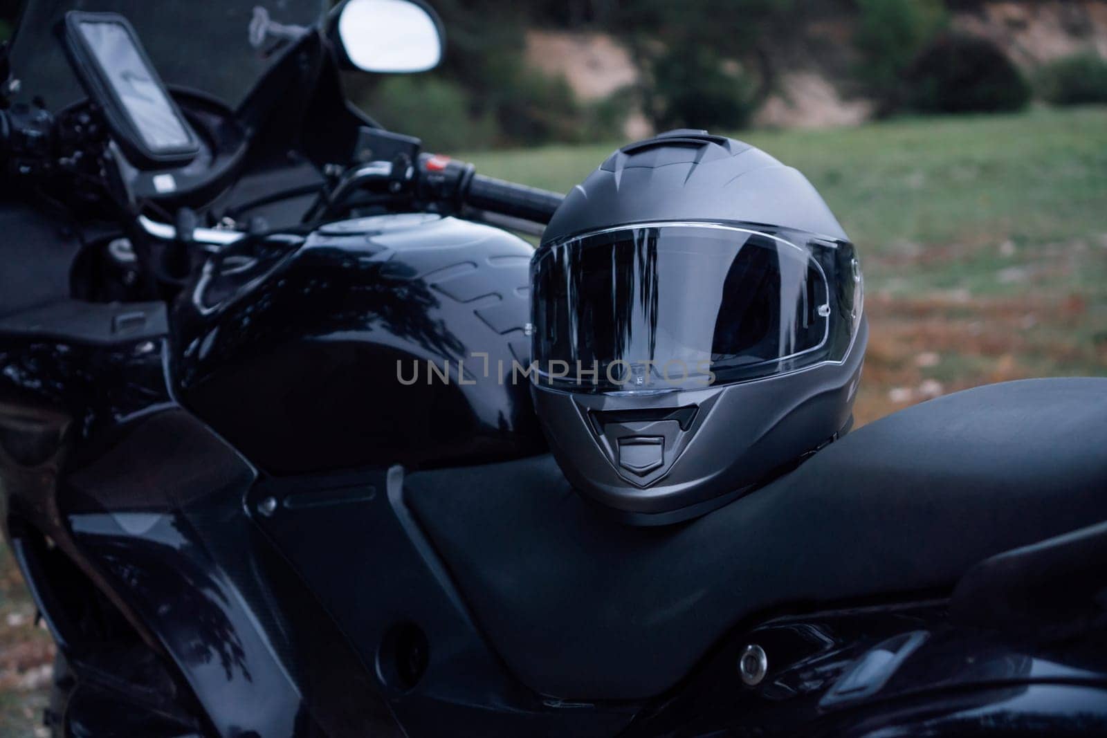 Motorcycle tourism. Close - up of black new motorcycle with helmet on seat is in nature .Tourism travel. Adventures vacations. Motorcycle gear. Motorcycle races .Hobbies and hobbieds.