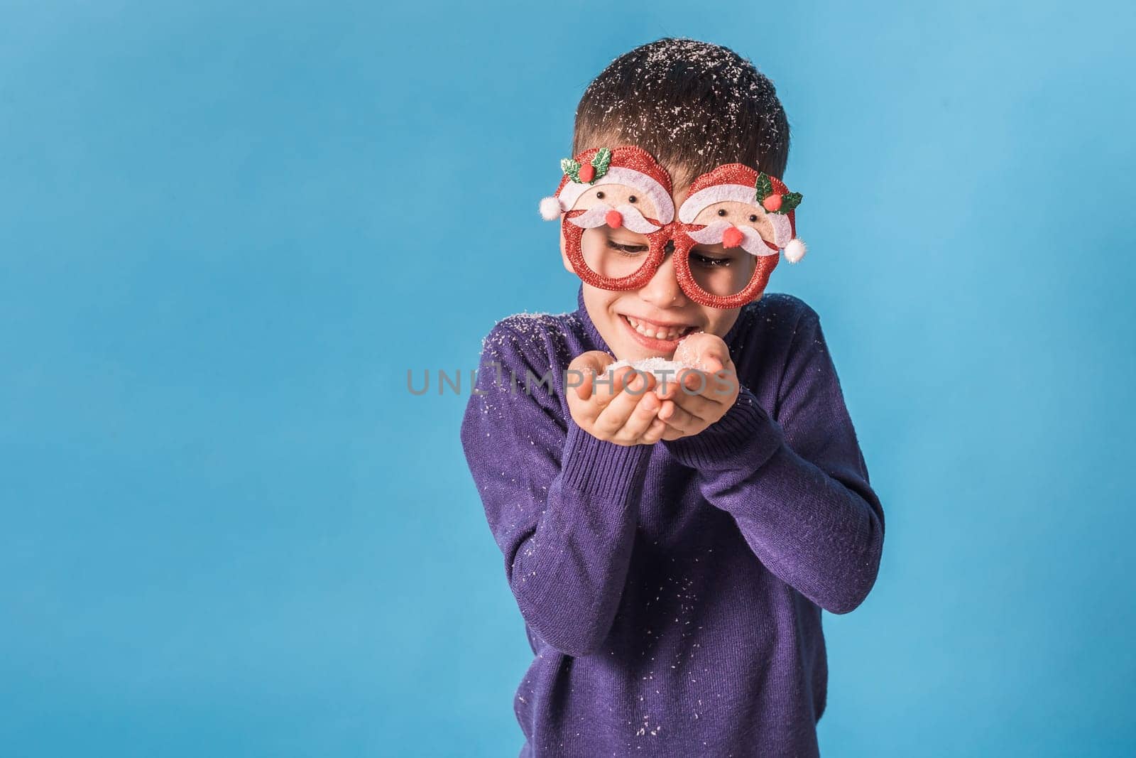 Child boy throws up on blue background. Christmas and New Year holidays concept. Generation alpha and gen alpha children. Copy space.