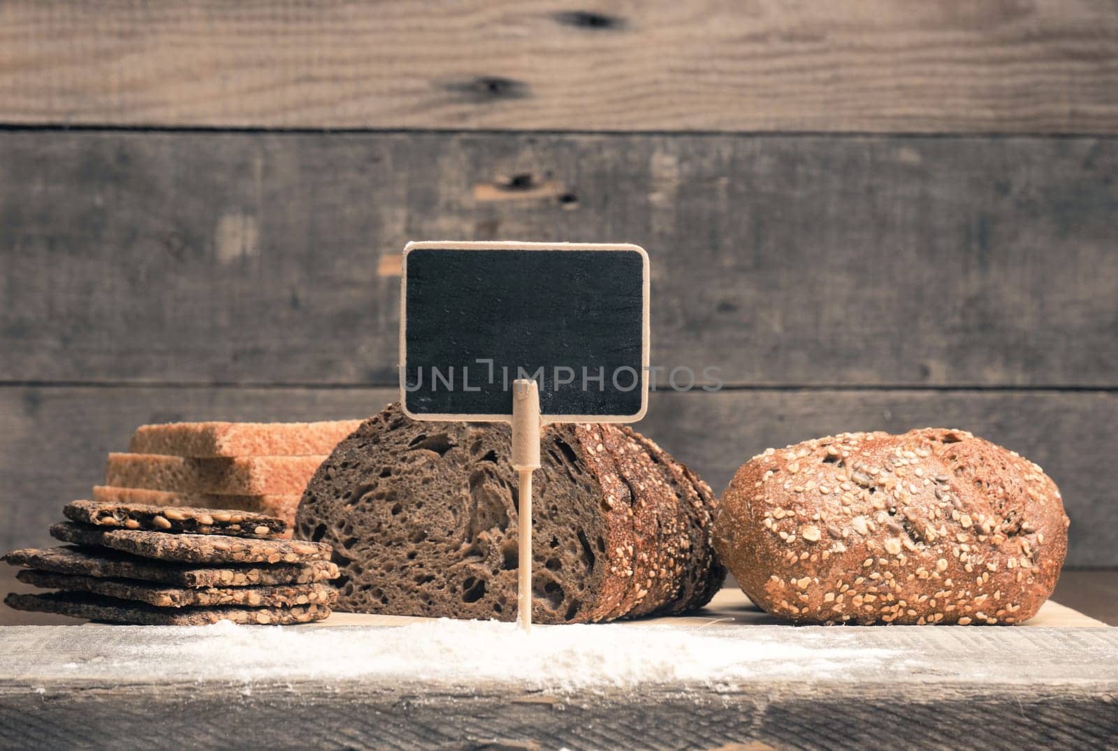 A small blank chalkboard with different types of bread as decoration, healthy food concept