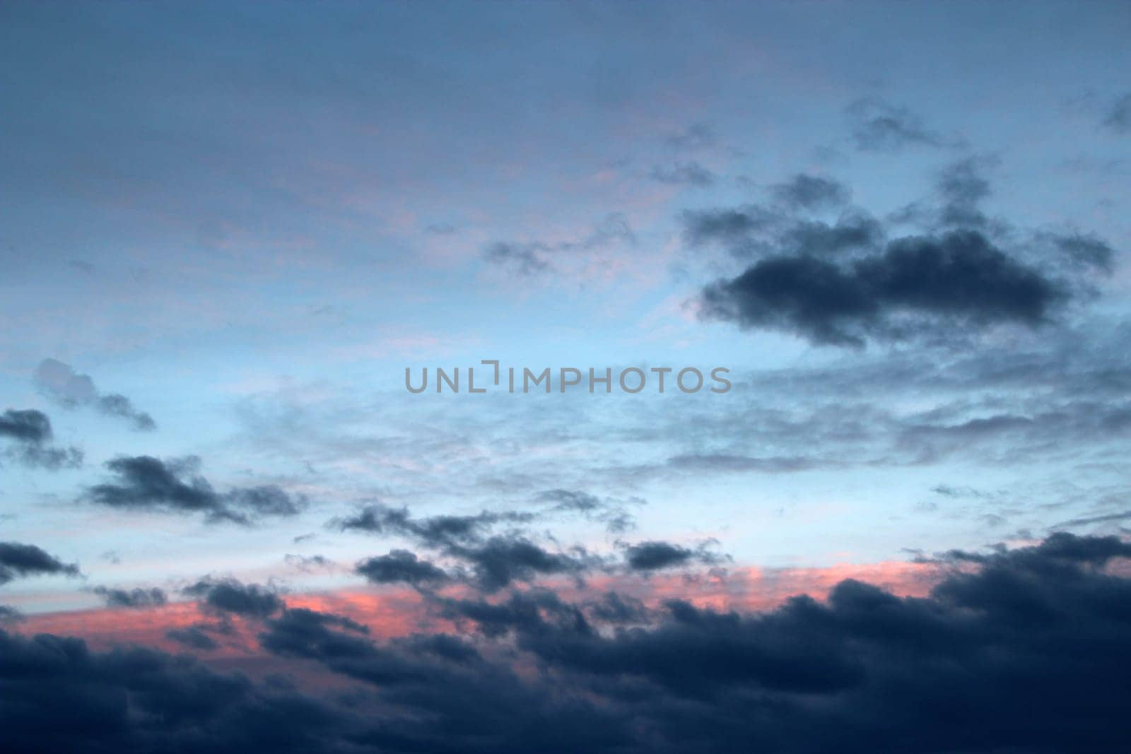 Heavenly landscape with pink clouds on purple sky during sunset. Beautiful evening sky with reddish clouds. Twilight with bright sunset. Sunny rays leaving with decline. Evening landscape