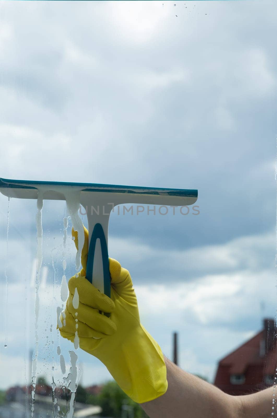Window cleaning with a scraper and window cleaner. Cleaning in a house or apartment. Removing dirt from windows and windows. High quality photo