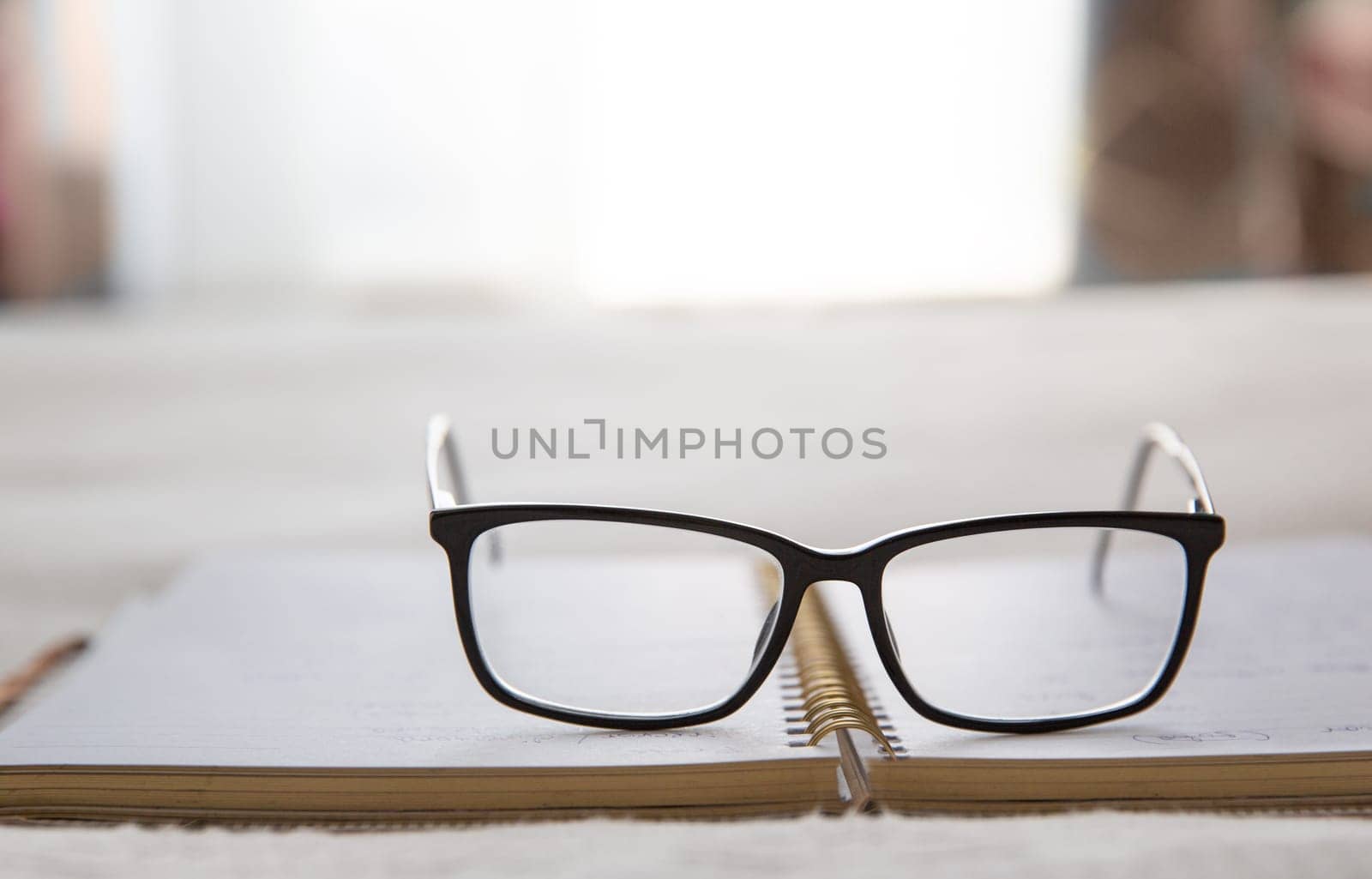 Image of an open notebook placed in bed with glasses at the top and a window in the background.blurred background. High quality photo