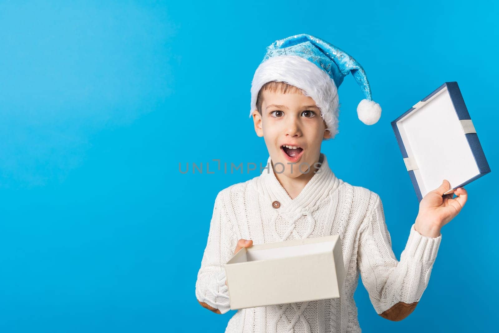 Child boy gift. Kid in blue christmas hat holds gift box. Shopping time. Banner header with copy space. Generation alpha and gen alpha