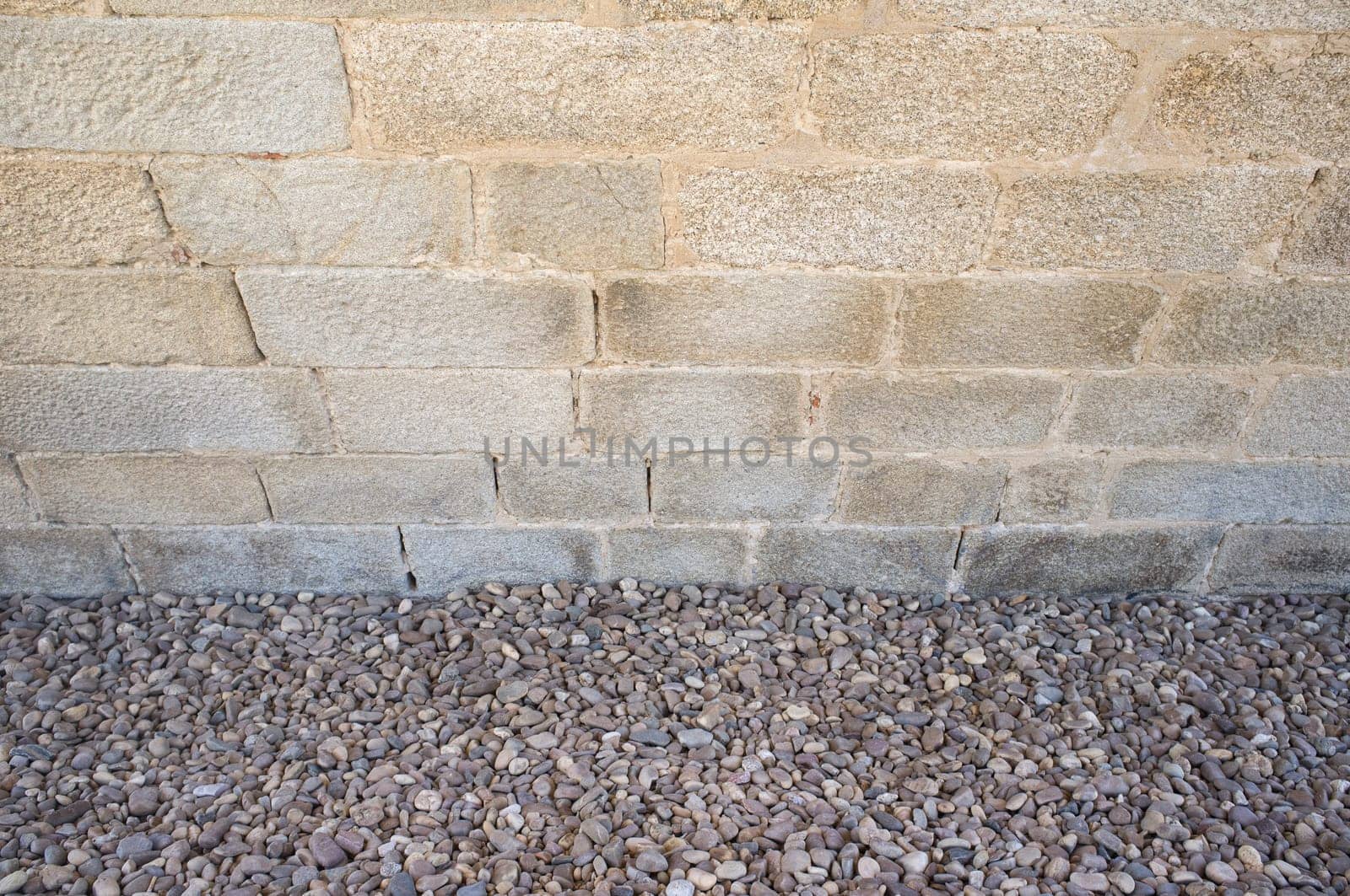 Granite ashlars wall with river pebble stones as ground. Flooring techiques for drainage