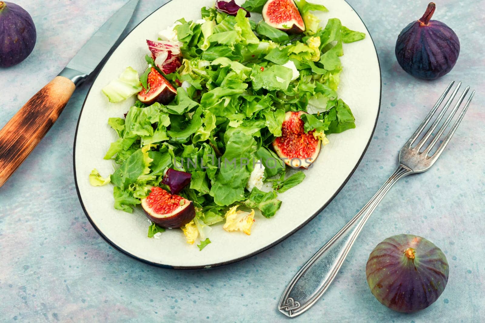 Seasonal fresh colorful salad of green leaves, ripe figs and diet cheese