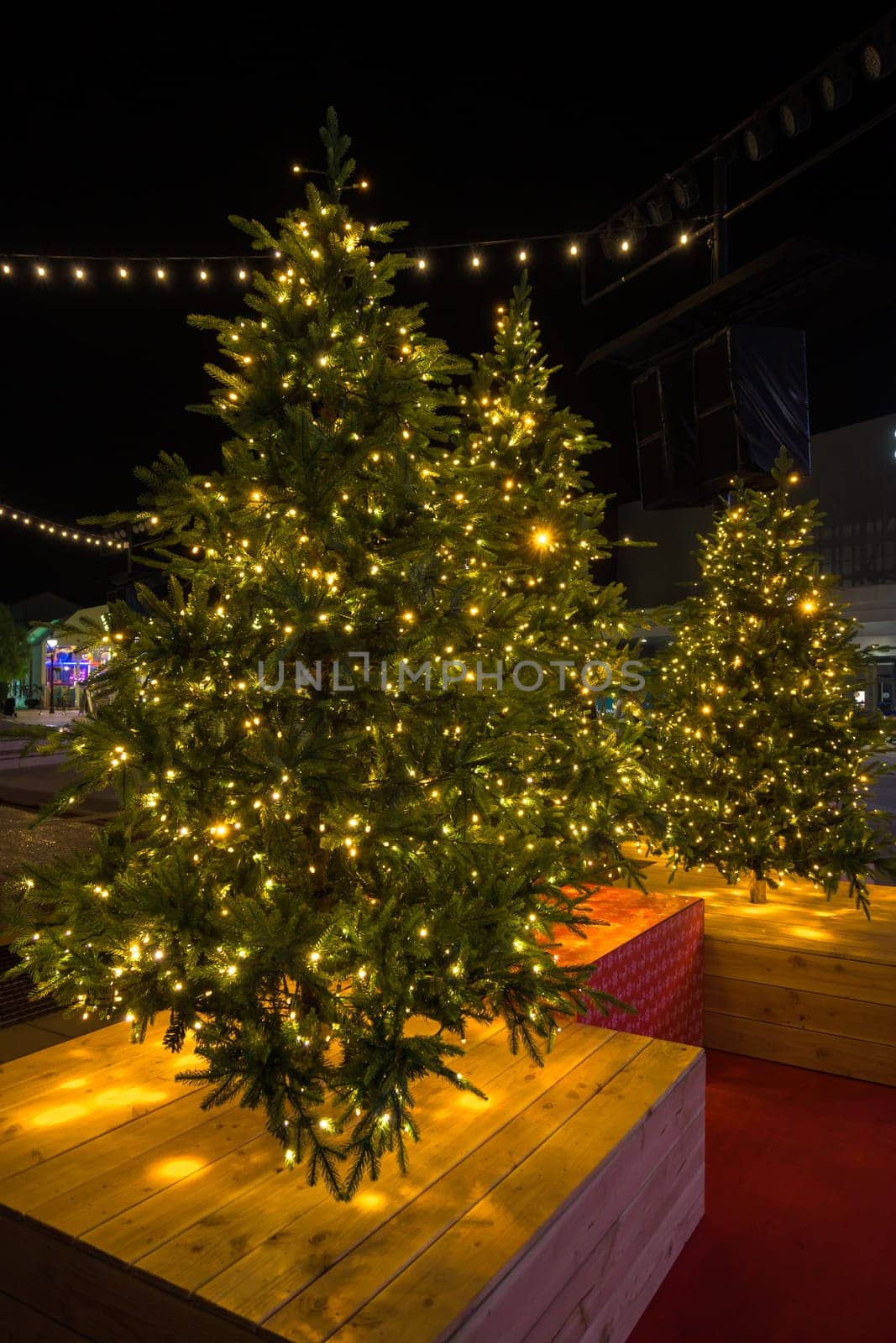 Christmas tree in pot with red decorations and lights outdoors near grey loft building