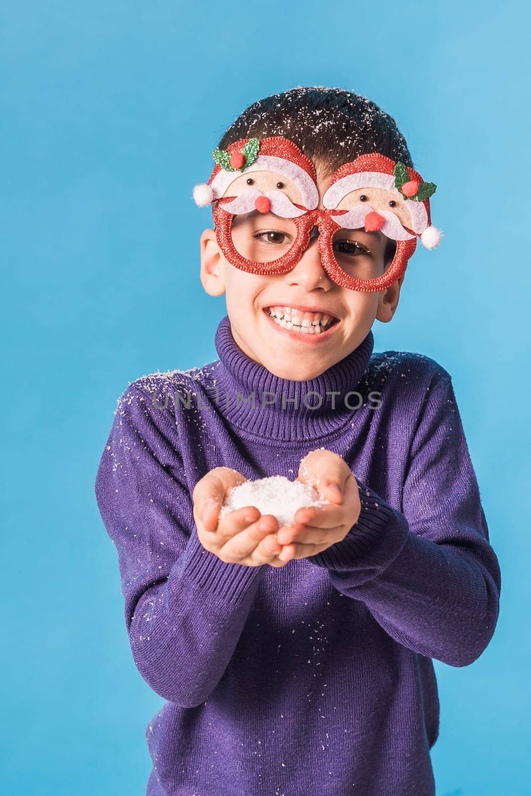 Child boy throws up on blue background. Christmas and New Year holidays concept. Generation alpha and gen alpha children. Copy space.