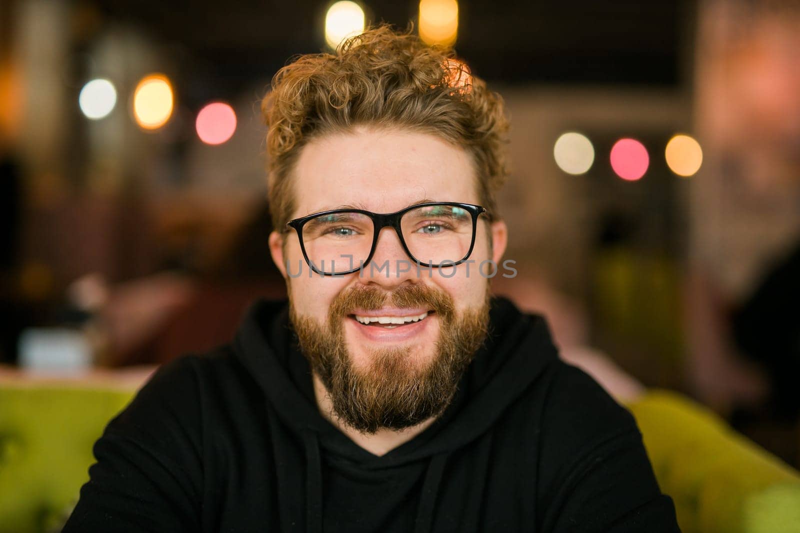 Close up portrait of young handsome freelance man wearing stylish eyeglasses on cafe. Happy confident student looking at camera, education and online work concept. Millennial generation and Gen Y