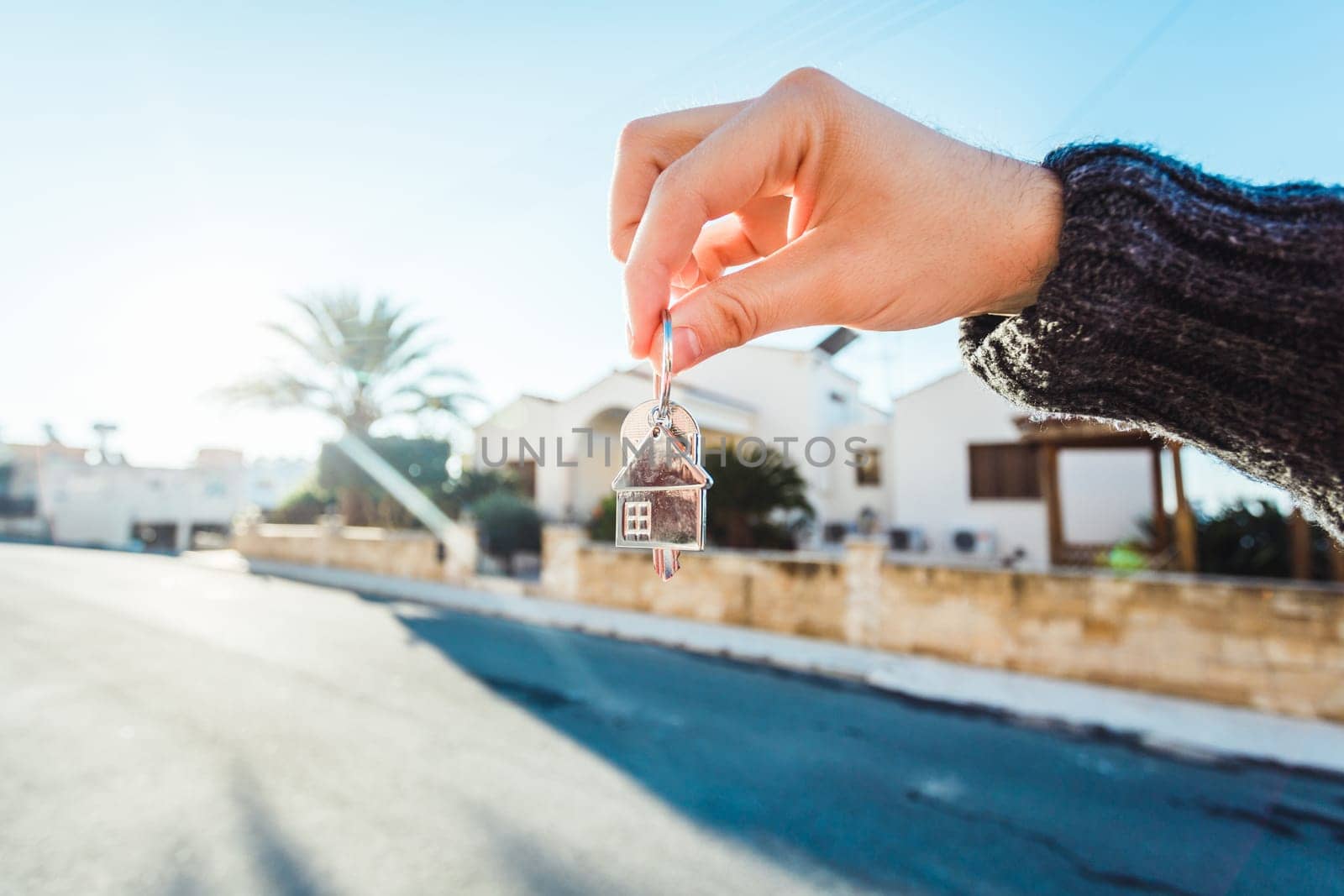 Holding house keys on house shaped keychain in front of a new home