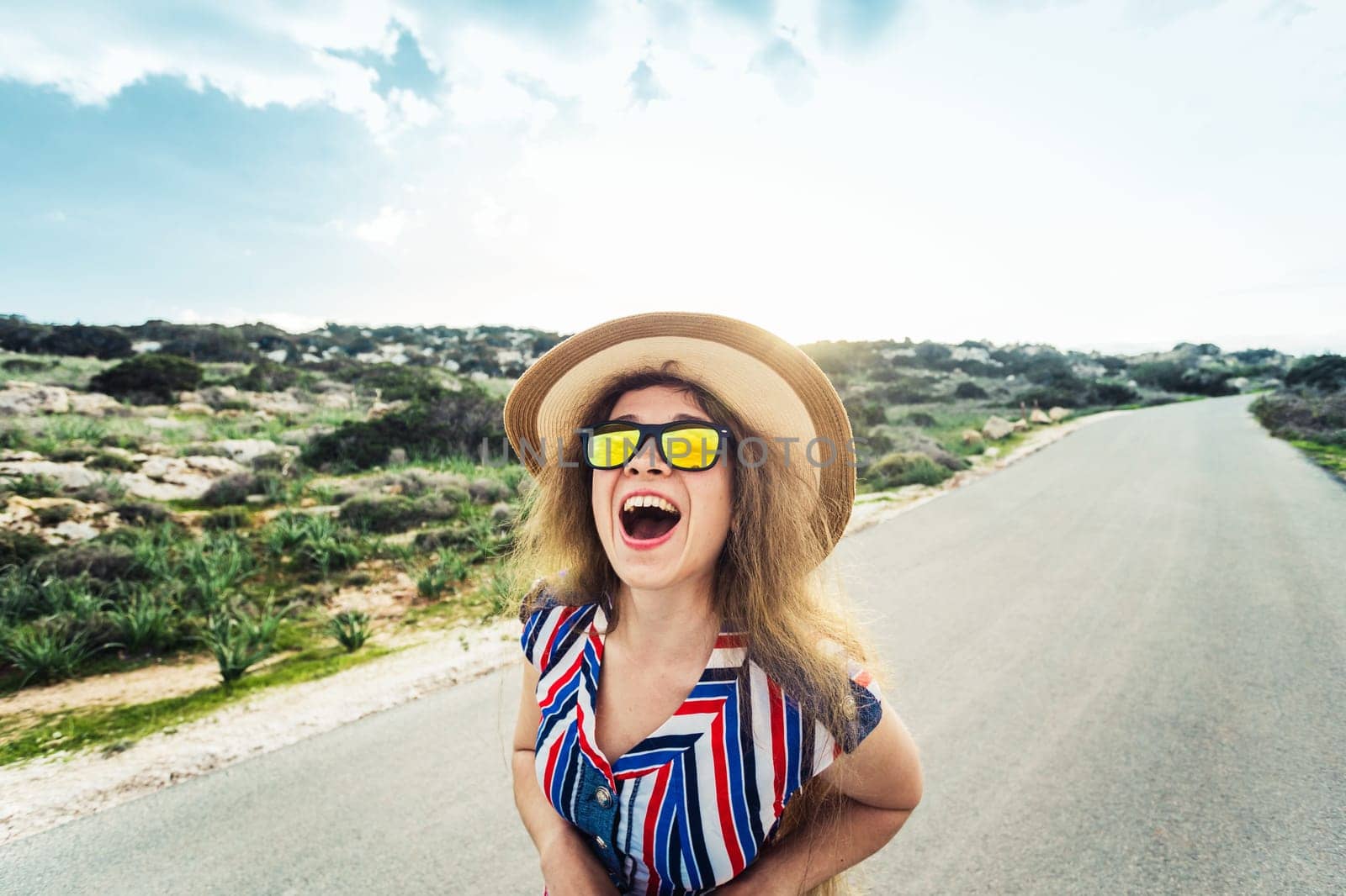 Closeup of delighted happy young blond pretty lady in sunglasses over blue sky on summer day outdoors background