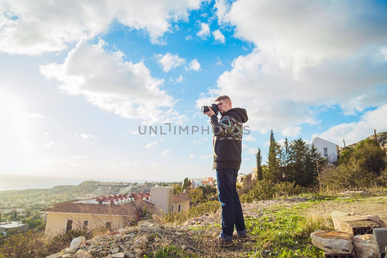 Young man with backpack taking a photo on the top of mountains, caucasian
