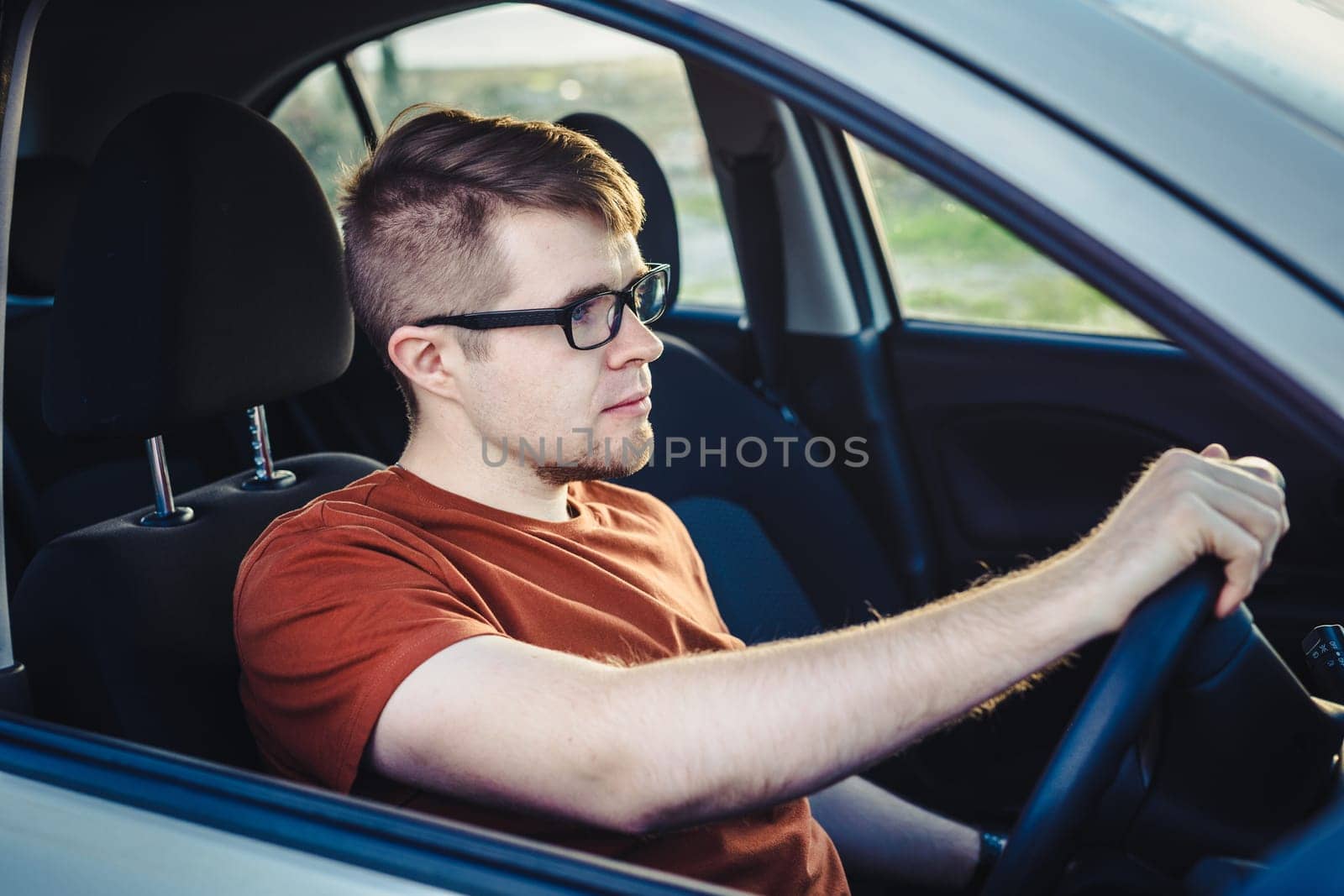 Attractive young man driving his new car.