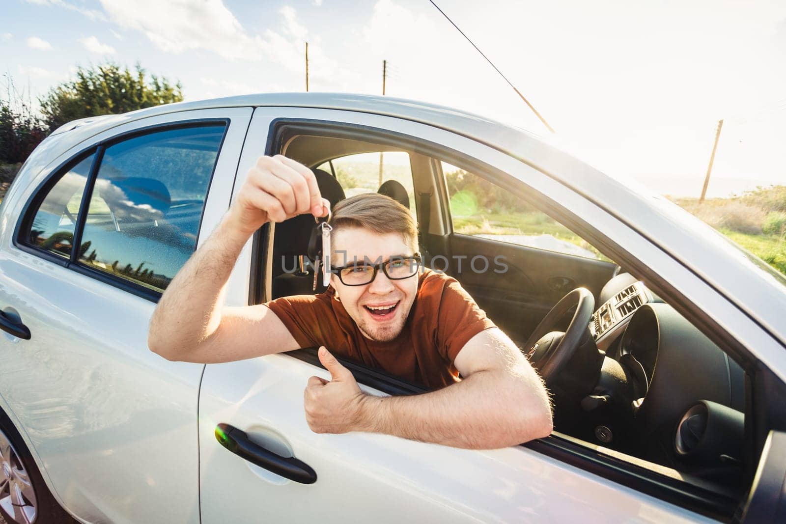 Attractive young happy man showing his new car keys and laughing.