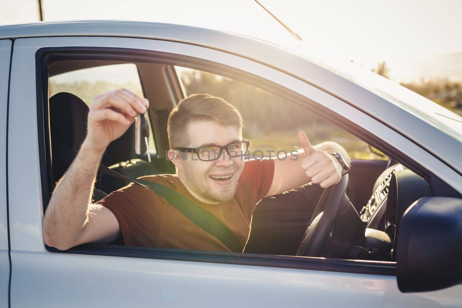 Attractive young man showing his new car keys and smiling.