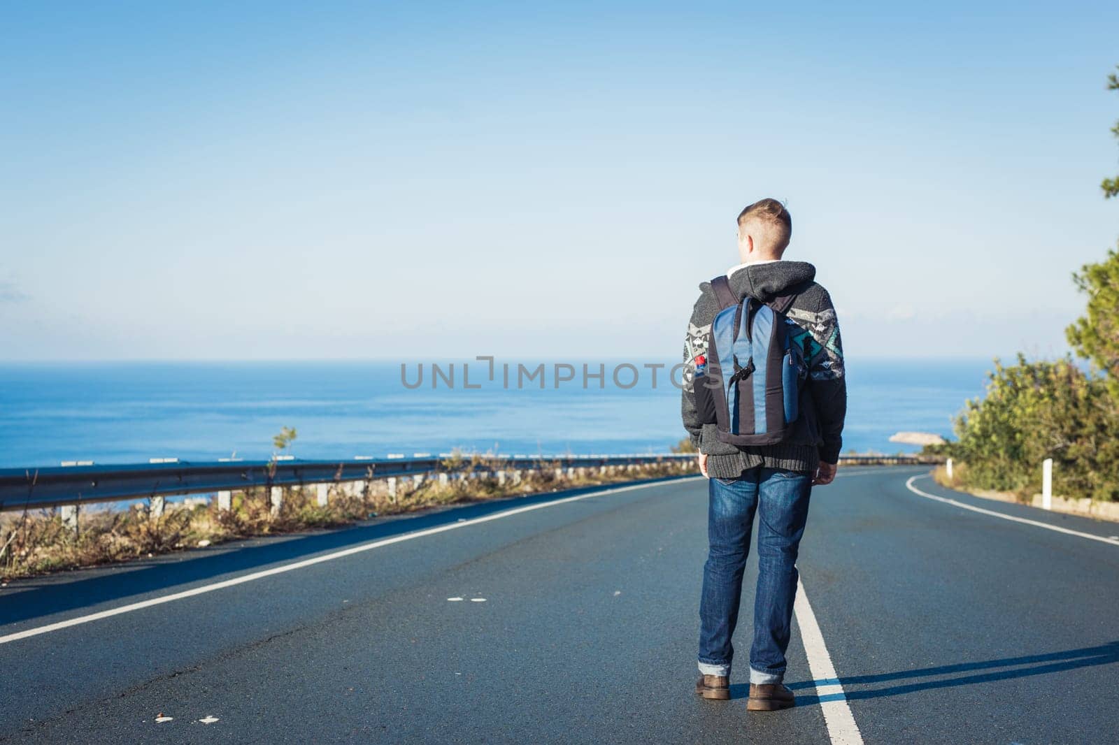 a man with a backpack walks alone on a mountain road